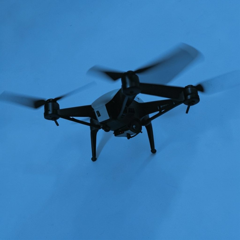 Drone flight training in progress, instructor and student reviewing a tablet with a drone nearby on a grassy field