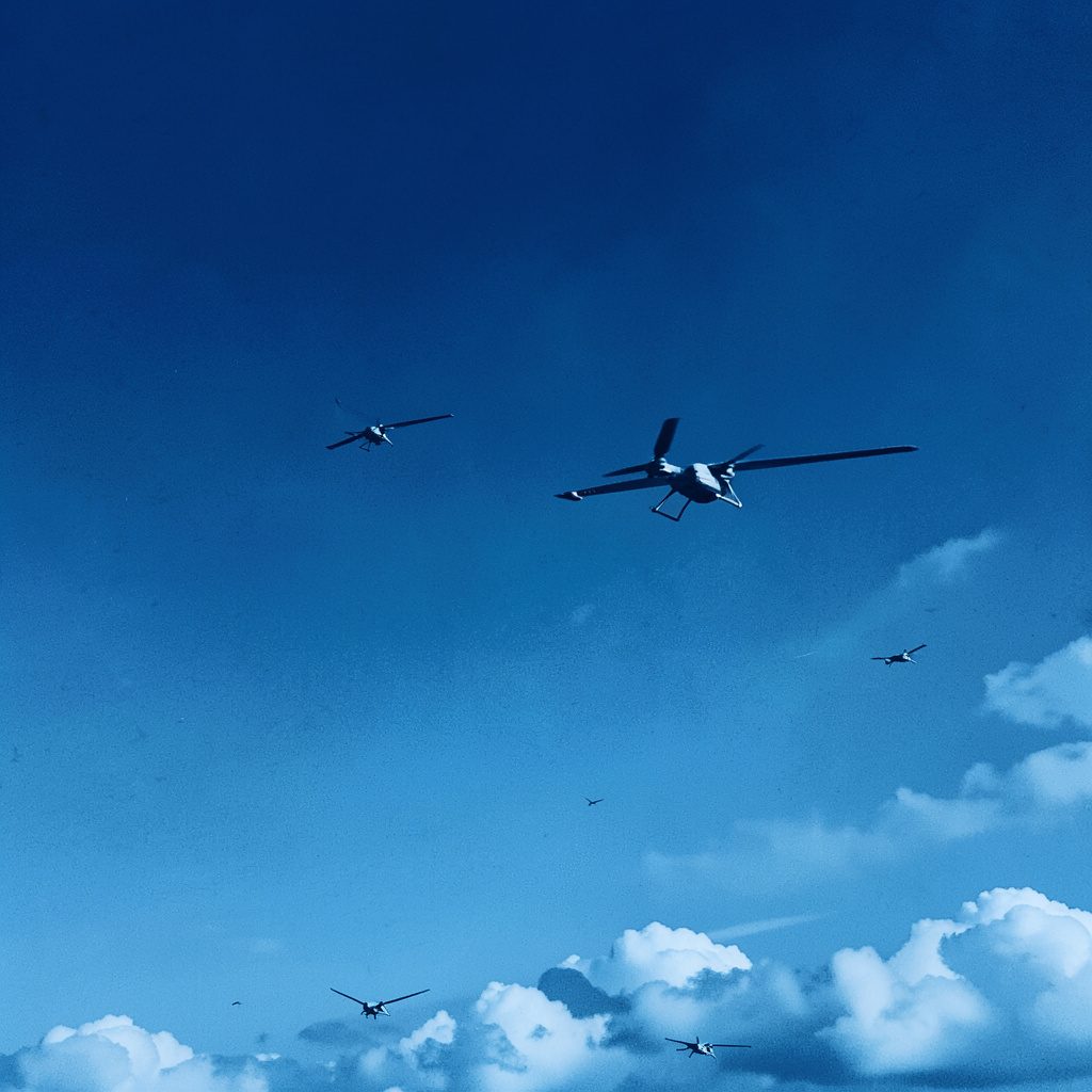 Blue sky with several small drones hovering at different heights, rendered in a crisp teal-and-coral duotone